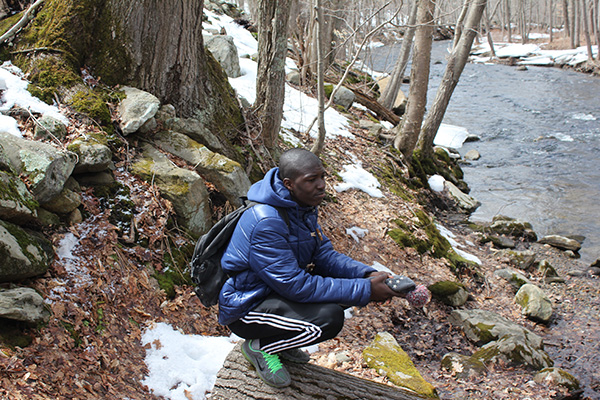 A student crouches streamside to observe how the shape of the land determines where water flows in a watershed.