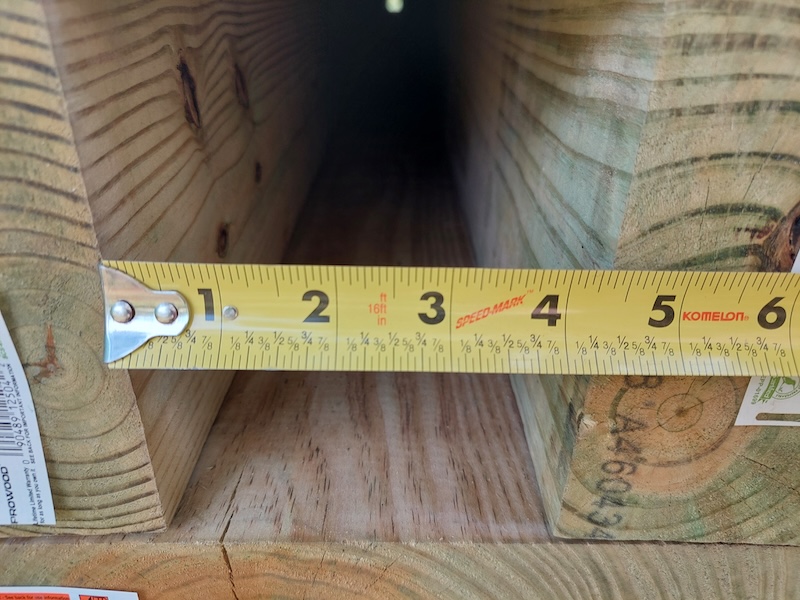 Measuring internal width. A tape measure measuring the width inside the culvert’s two side walls.