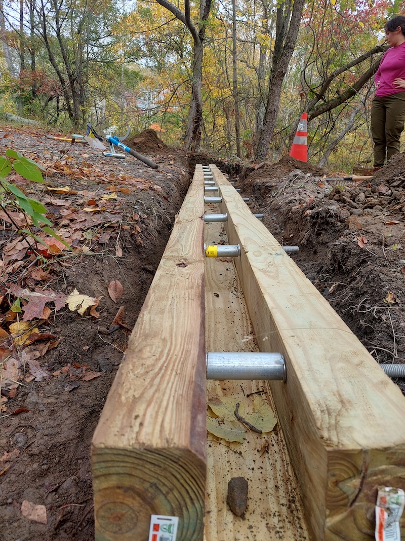 Culvert installation. Open-top box culvert sits in a trench dug into the road.