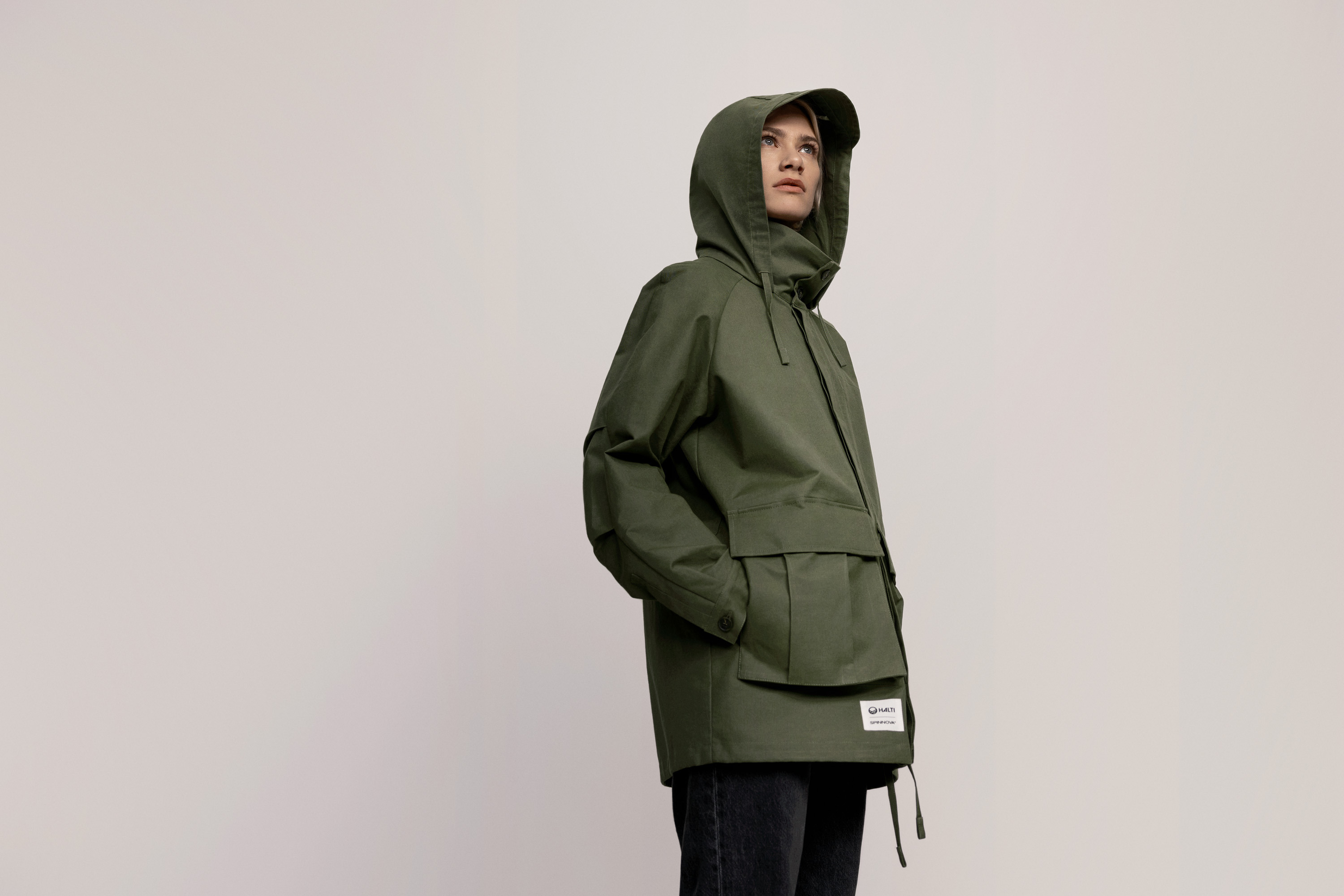 A woman wearing a dark green hooded parka made from Spinnova fiber.