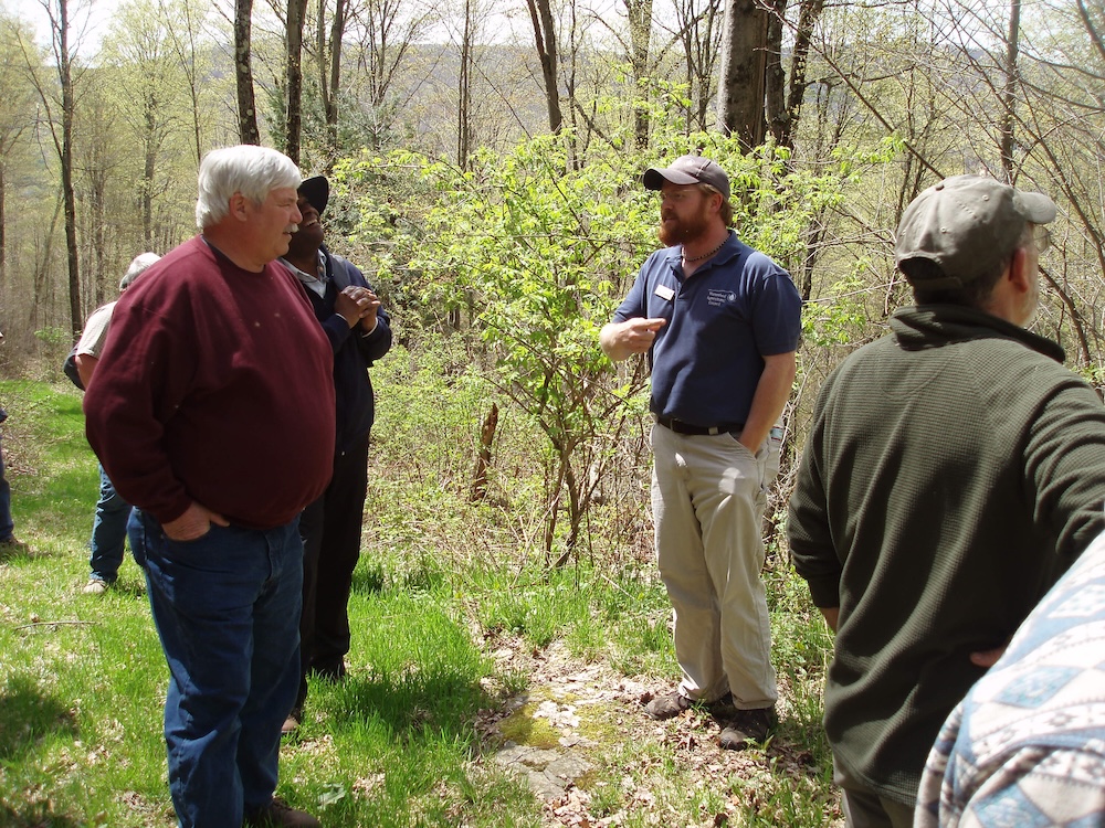 A landowner woods walk. A presenter sharing knowledge at a workshop in the woods in the spring.