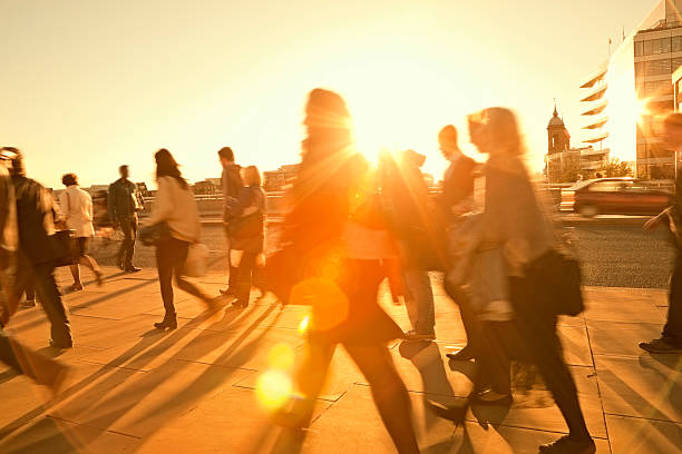 People walking across a hot, treeless, sunlit area in a city.