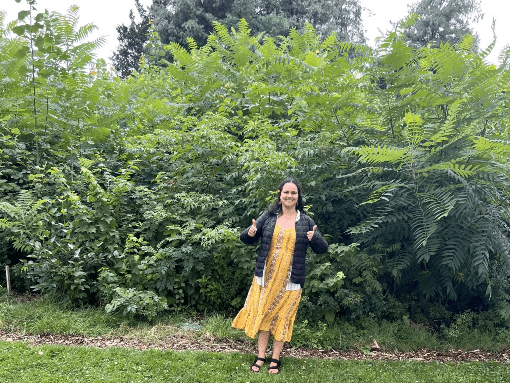 A woman at the planting site with two years of growth on the mini woods behind her.