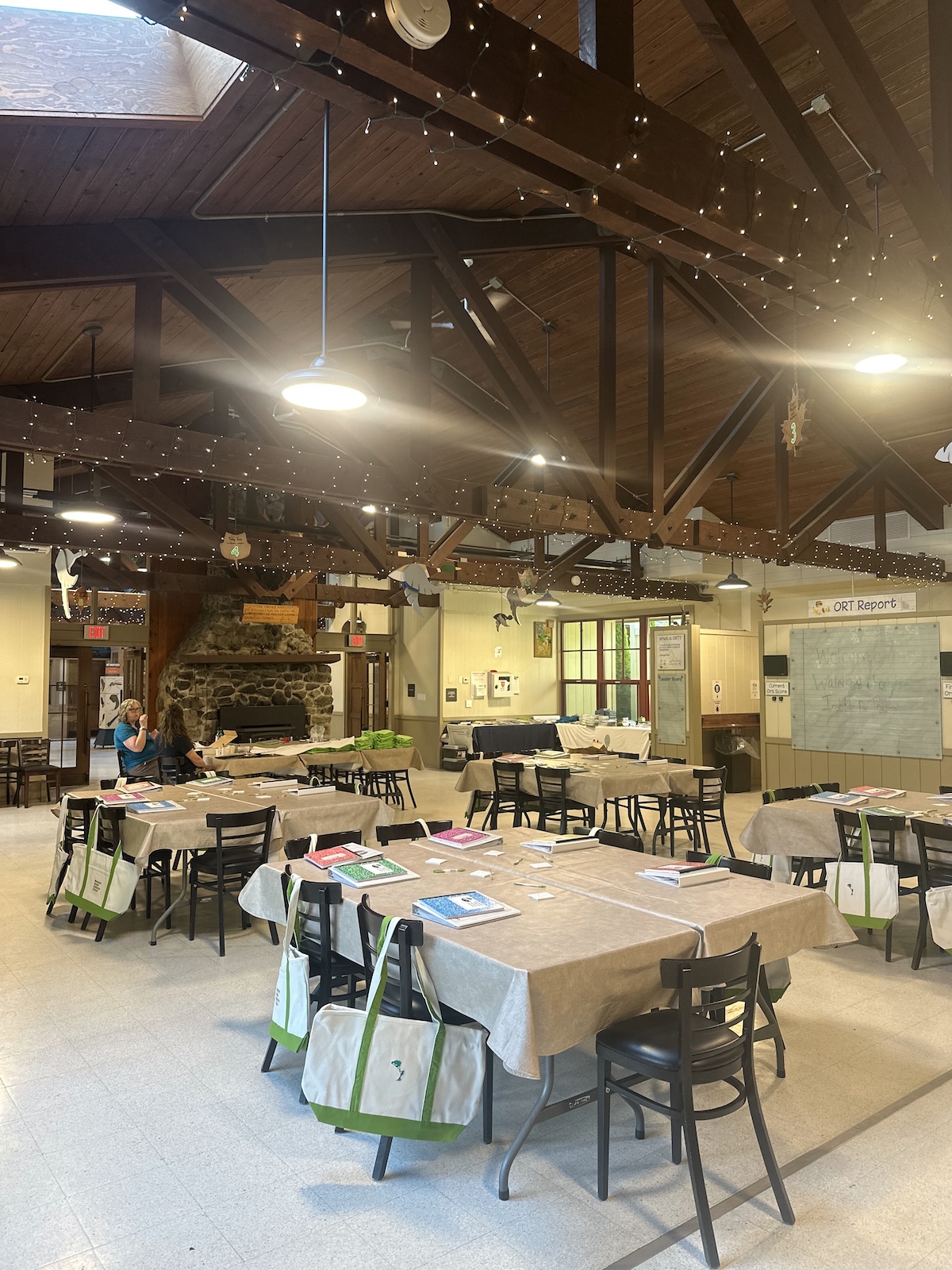 The main lodge before participants arrived. 5 tables are prepared with notebooks, binders, and a tote bag. 