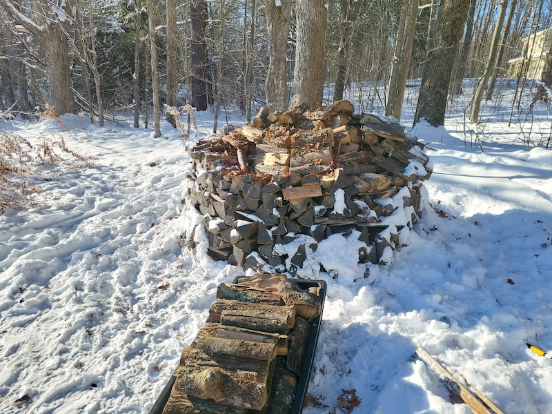 Jet sled Load #3 with the holz hausen in the background. All of the shingles have been removed and the wood pieces are still mounded on top.